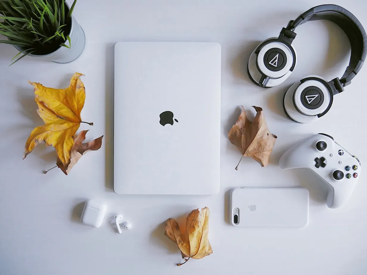 macbook beside headphones and a plant