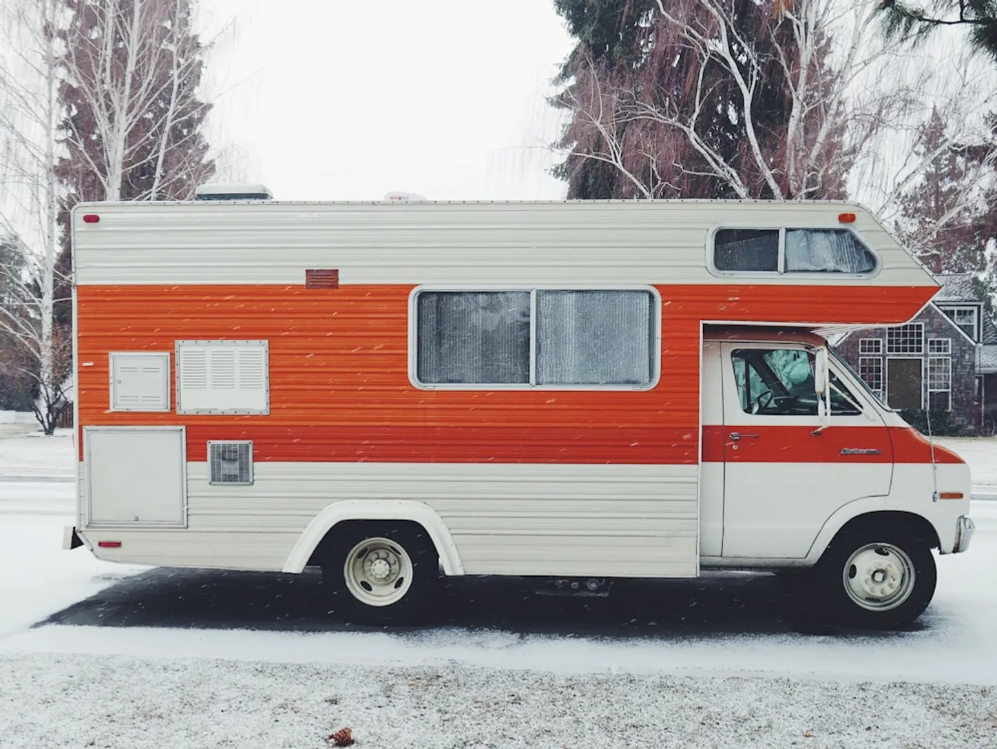 orange and white class a motorhome surrounded by snow